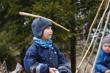 Kindheit Filmstill - Junge trägt einen blauen Ast am Kopf im Wald