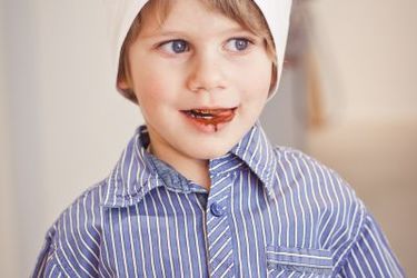 Bub mit weißer Kochmütze, Schokolade auf den Lippen