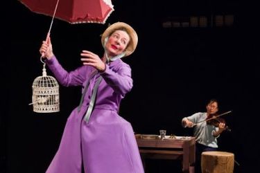 Foto aus dem Theaterpsiel - Frau mit Schirm und langem violettem Kleid
